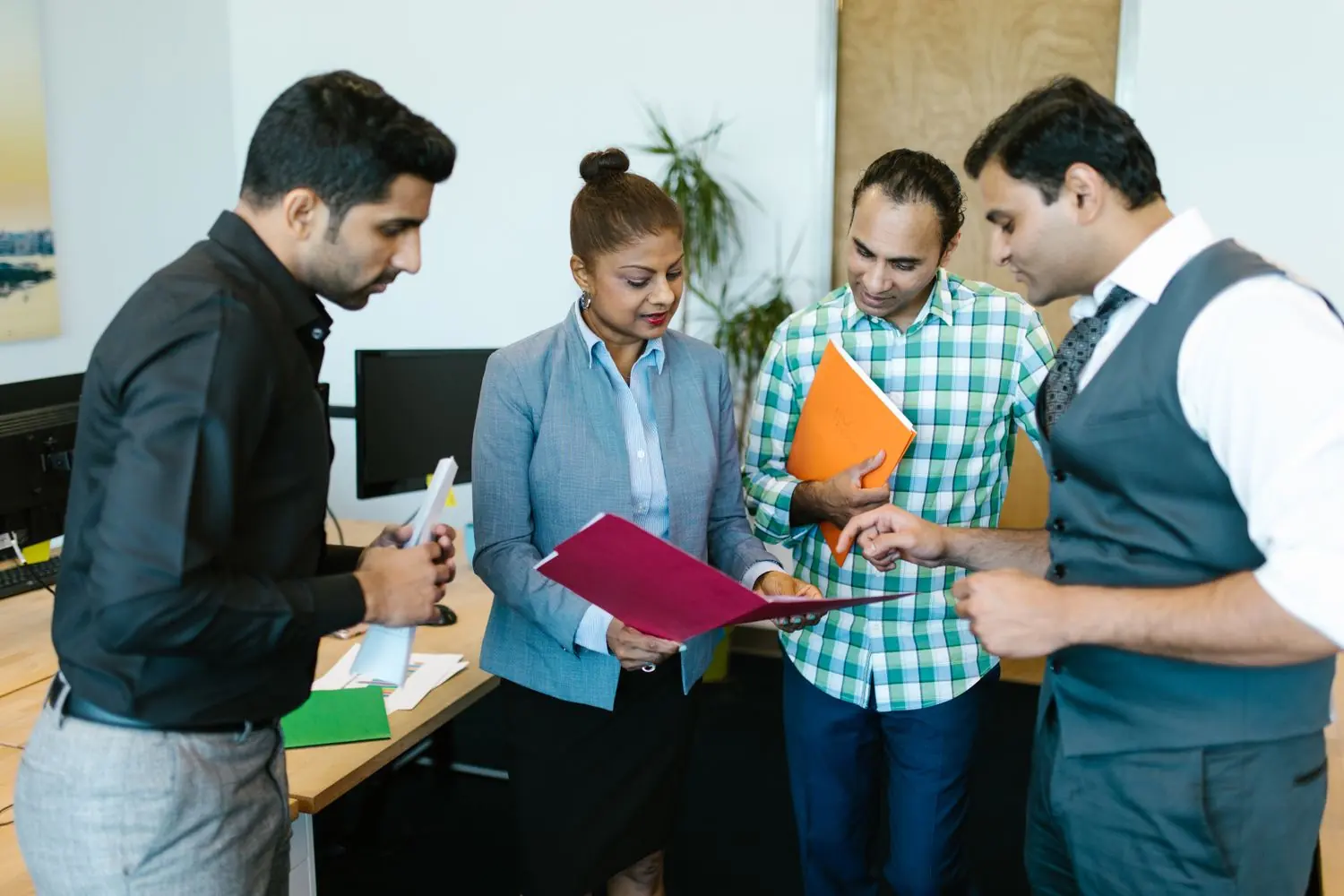 Four colleagues reviewing application documents together in an office